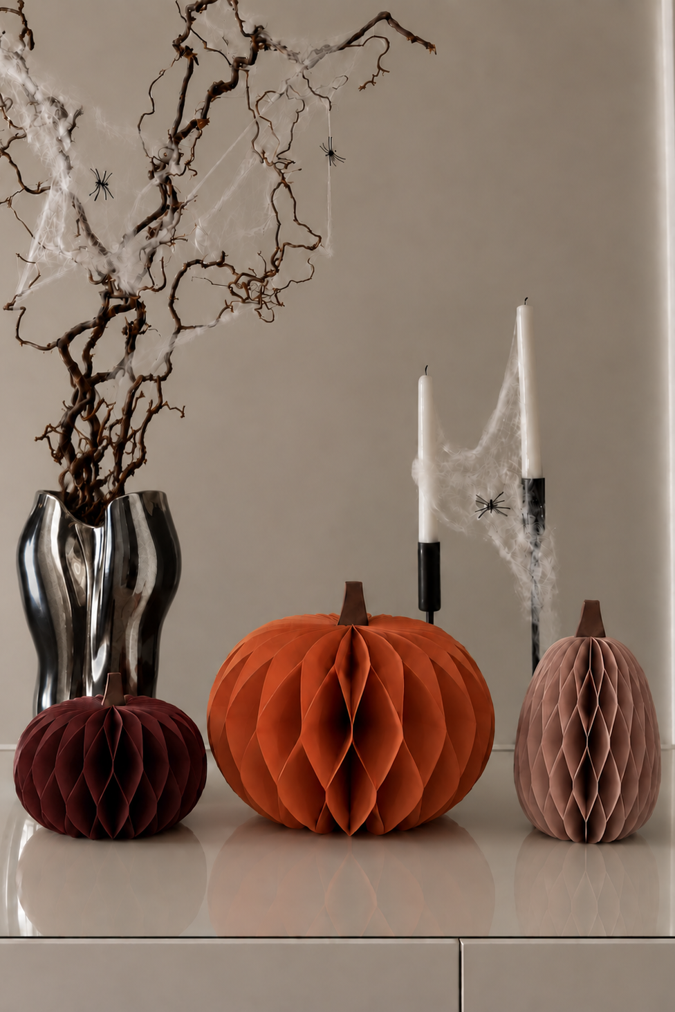 Papierkürbisse in Orange, Rot und Rosa auf einem weißen Sideboard