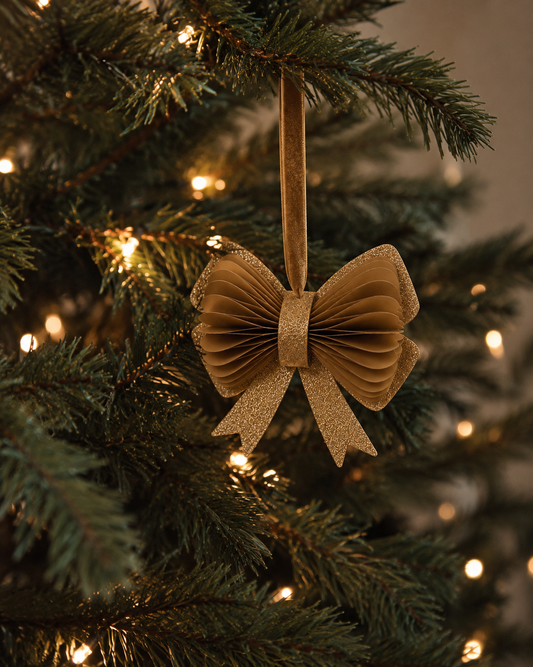 Goldene Papierschleife als Anhänger an einem beleuchteten Weihnachtsbaum